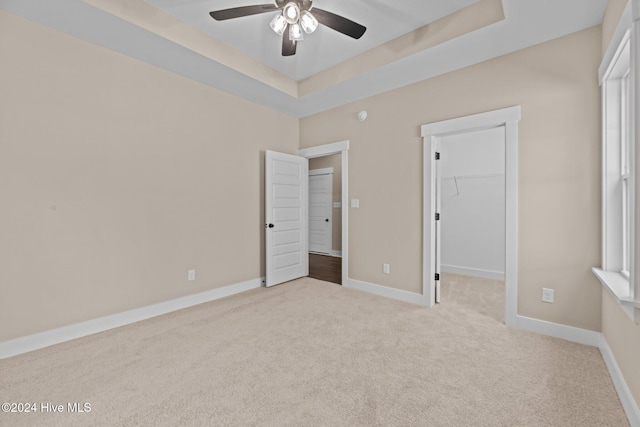 unfurnished bedroom featuring ceiling fan, light colored carpet, a spacious closet, and a closet