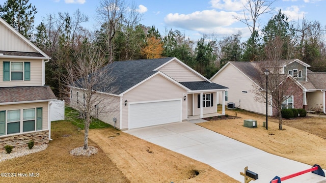 view of front property featuring central air condition unit, a front yard, and a garage