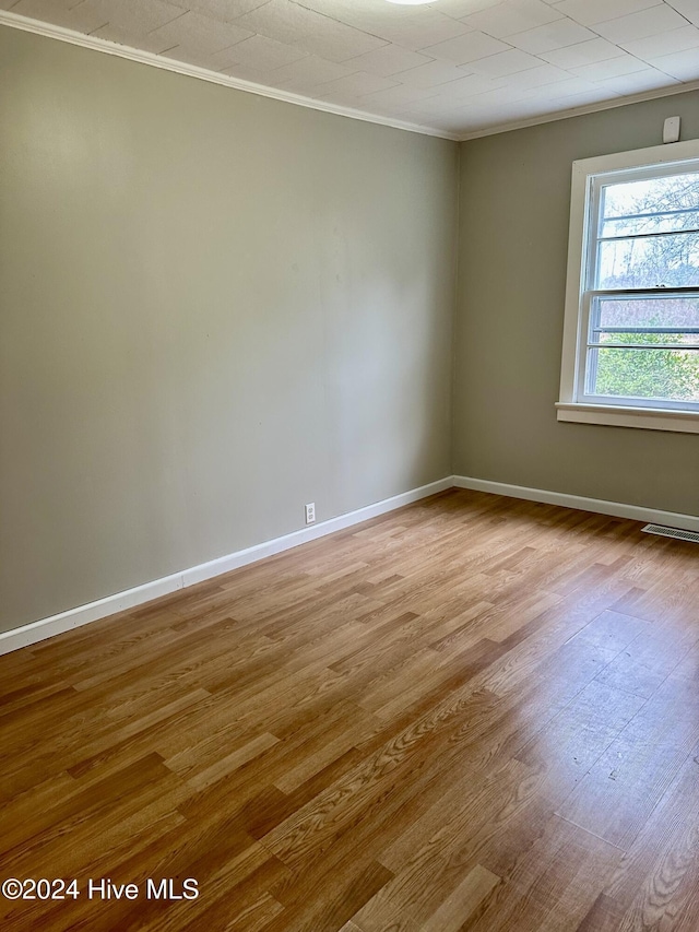 empty room featuring ornamental molding and light wood-type flooring