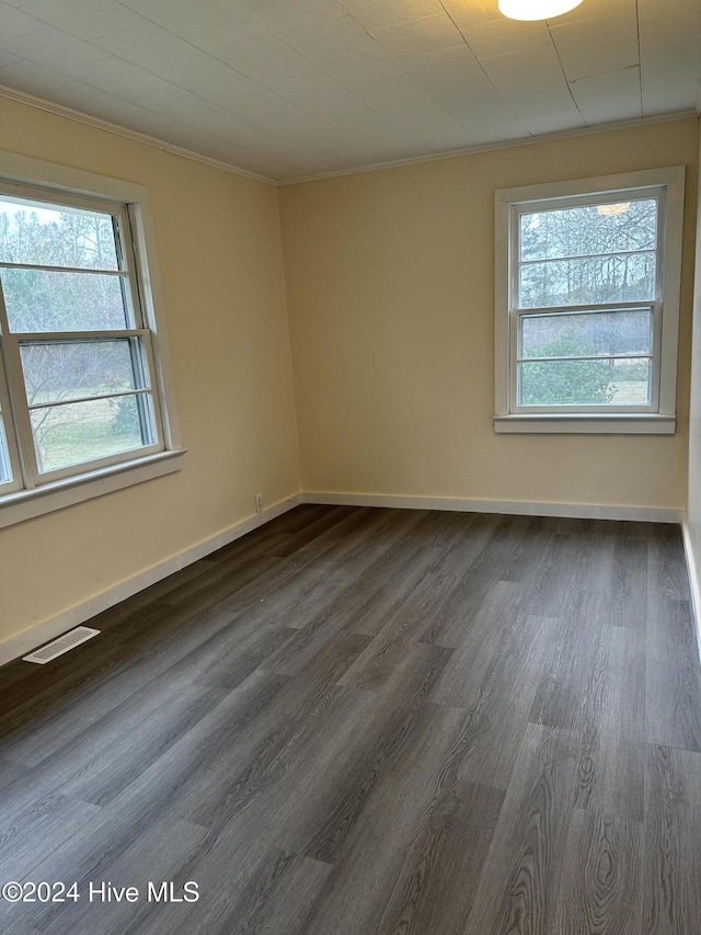 empty room featuring dark wood-type flooring and ornamental molding