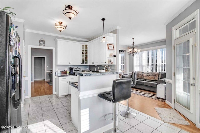 kitchen with white cabinets, stainless steel fridge, and light tile patterned floors