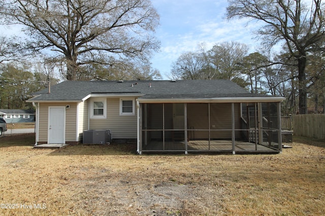 back of property with central AC, a sunroom, and a lawn