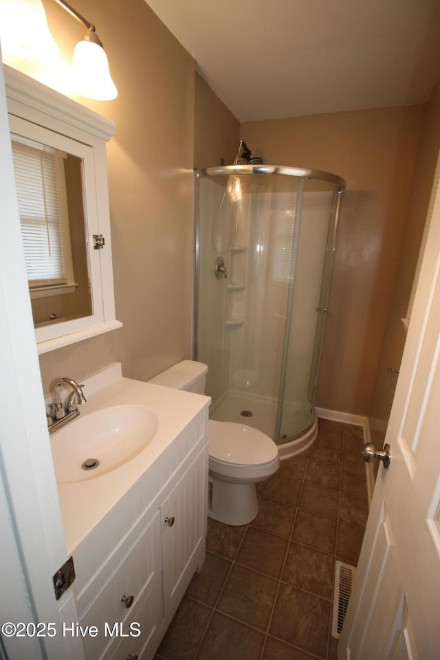 bathroom featuring toilet, vanity, tile patterned floors, and walk in shower