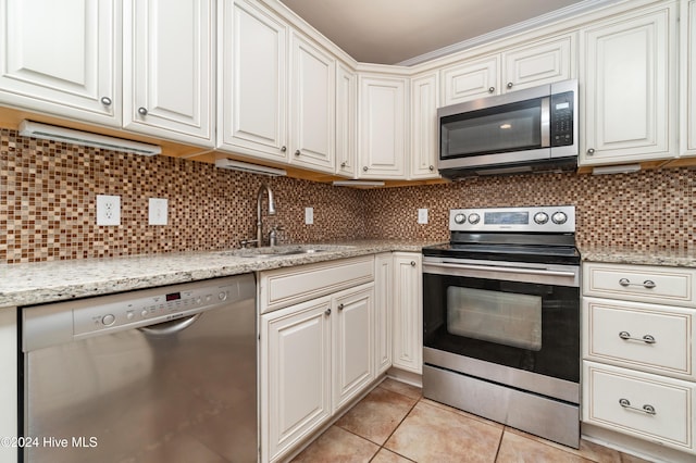 kitchen with sink, light tile patterned floors, backsplash, and appliances with stainless steel finishes