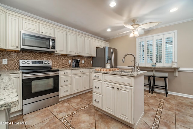 kitchen featuring light stone countertops, sink, crown molding, a kitchen island with sink, and appliances with stainless steel finishes