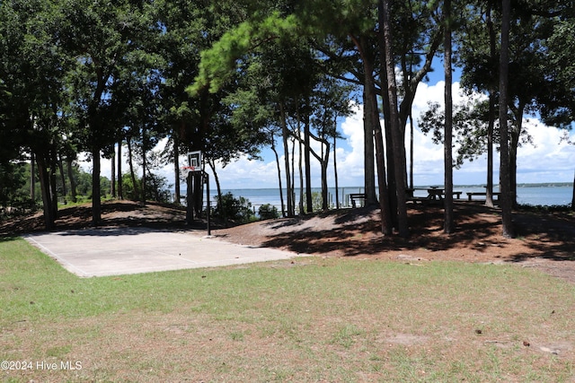 view of yard featuring basketball hoop and a water view