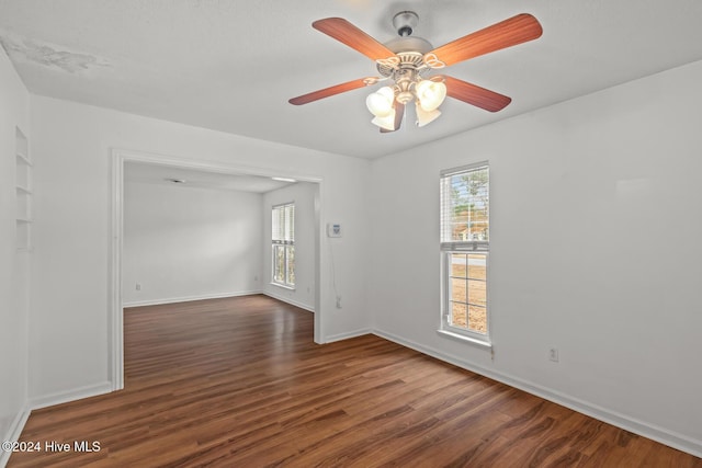 empty room featuring dark wood-type flooring, ceiling fan, and a healthy amount of sunlight