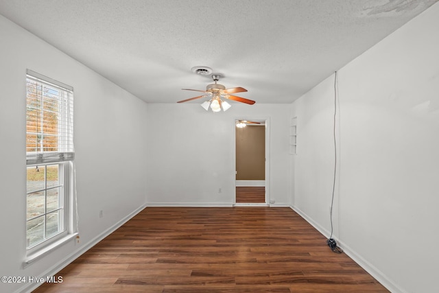 unfurnished room with a textured ceiling, ceiling fan, and dark wood-type flooring