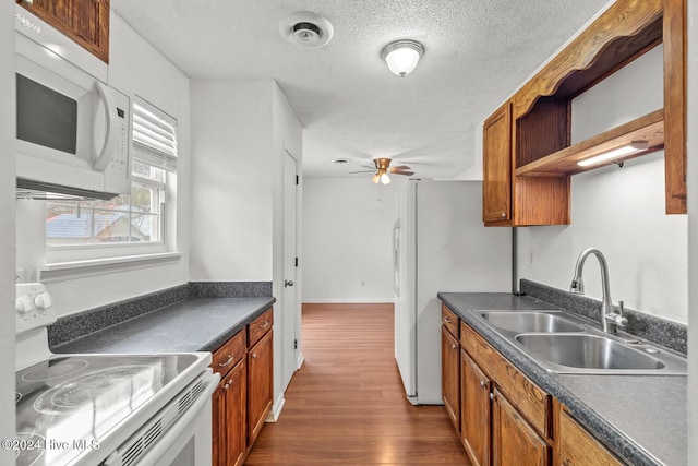 kitchen with ceiling fan, sink, dark wood-type flooring, stove, and a textured ceiling