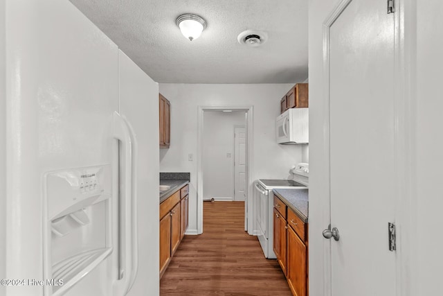 kitchen featuring dark hardwood / wood-style flooring, white appliances, and a textured ceiling