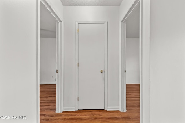 corridor featuring a textured ceiling and light hardwood / wood-style flooring