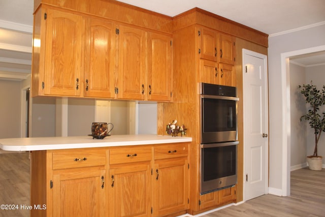 kitchen with kitchen peninsula, crown molding, double oven, and light hardwood / wood-style flooring