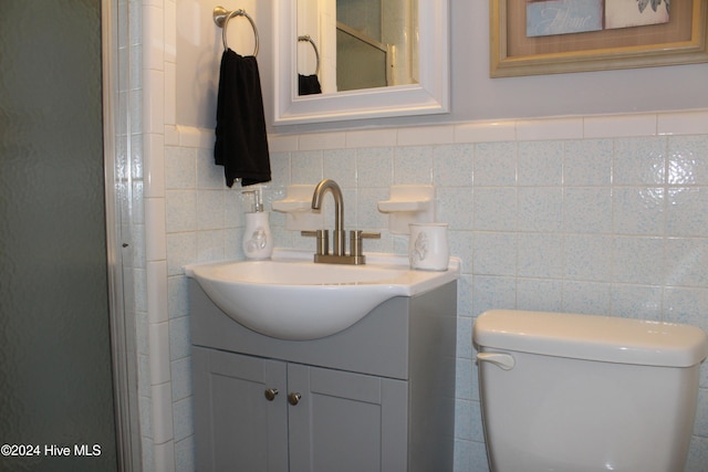 bathroom with vanity, tile walls, and toilet