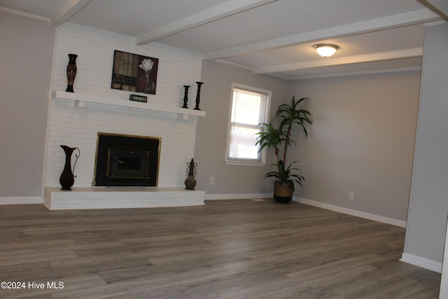 unfurnished living room with hardwood / wood-style flooring, a fireplace, crown molding, and beamed ceiling