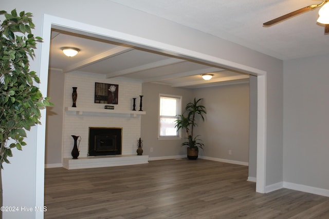 unfurnished living room with beamed ceiling, ceiling fan, dark hardwood / wood-style flooring, and a brick fireplace