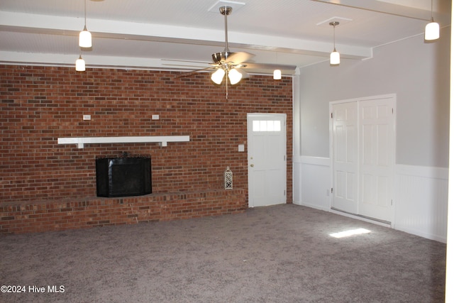 unfurnished living room with carpet flooring, beam ceiling, ceiling fan, brick wall, and a fireplace