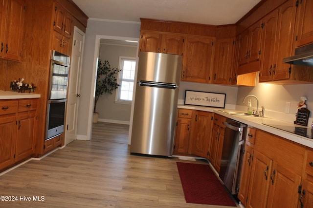 kitchen featuring appliances with stainless steel finishes, ornamental molding, extractor fan, sink, and light hardwood / wood-style flooring