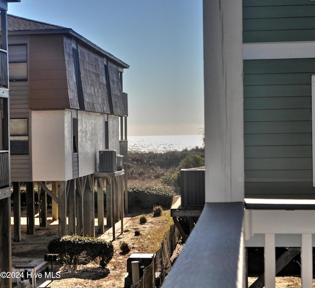 view of side of home featuring central AC unit and a water view