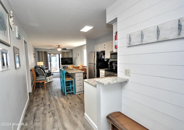 kitchen with white cabinetry, ceiling fan, stainless steel appliances, a breakfast bar area, and light wood-type flooring