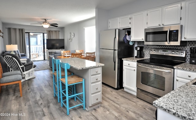 kitchen featuring a center island, ceiling fan, tasteful backsplash, white cabinetry, and stainless steel appliances