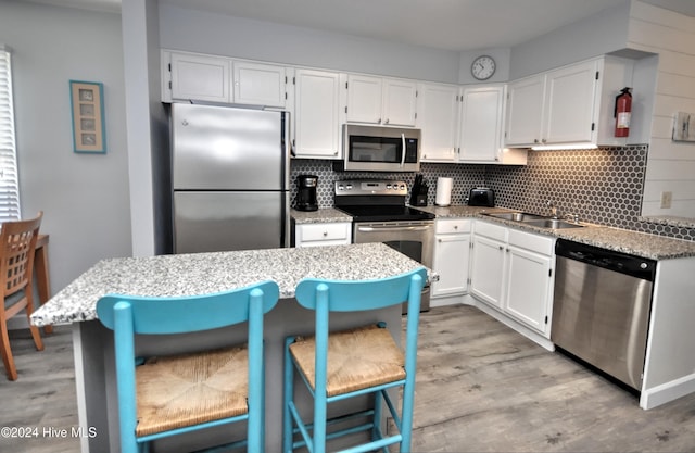 kitchen with a kitchen bar, stainless steel appliances, white cabinetry, and sink