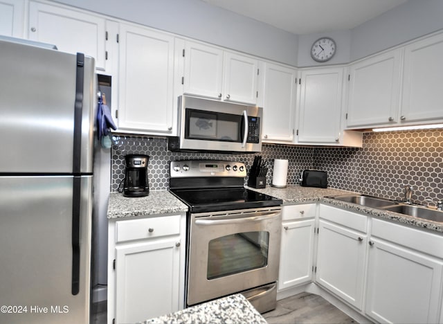 kitchen featuring white cabinets, appliances with stainless steel finishes, decorative backsplash, and sink