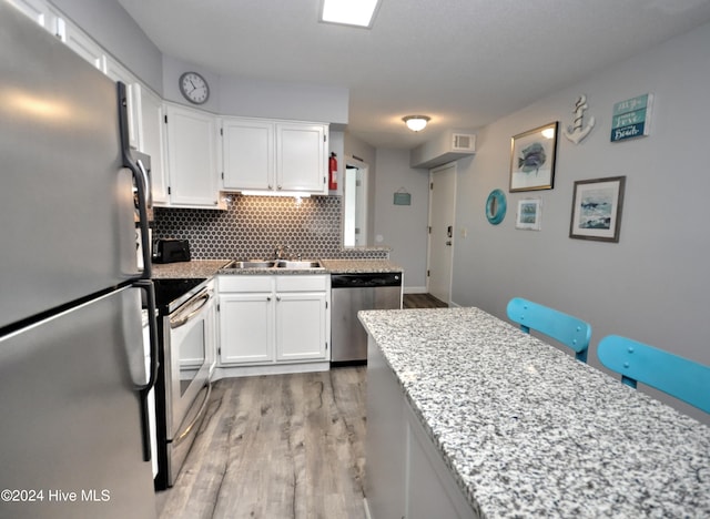 kitchen with decorative backsplash, light wood-type flooring, stainless steel appliances, sink, and white cabinetry