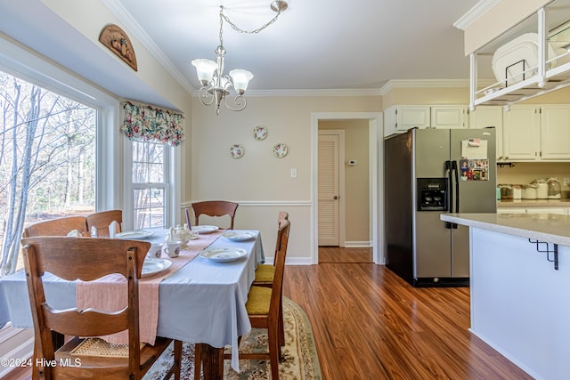 dining space with dark hardwood / wood-style flooring, ornamental molding, and an inviting chandelier