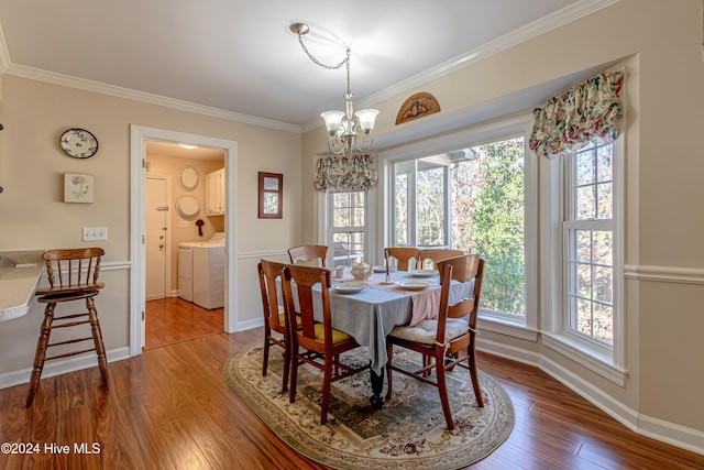 dining space featuring ornamental molding, washer and dryer, a notable chandelier, and hardwood / wood-style flooring