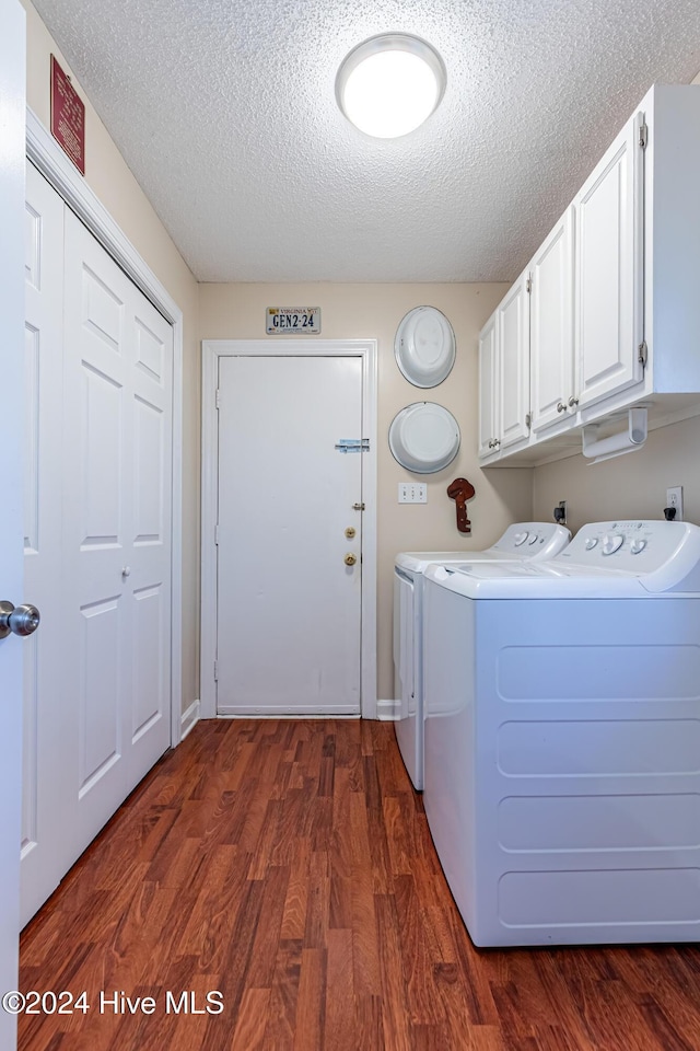 clothes washing area featuring cabinets, a textured ceiling, dark wood-type flooring, and washing machine and clothes dryer