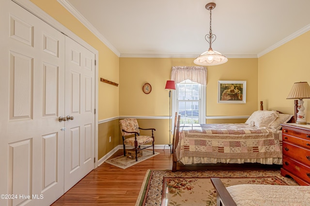 bedroom with hardwood / wood-style floors, crown molding, and a closet