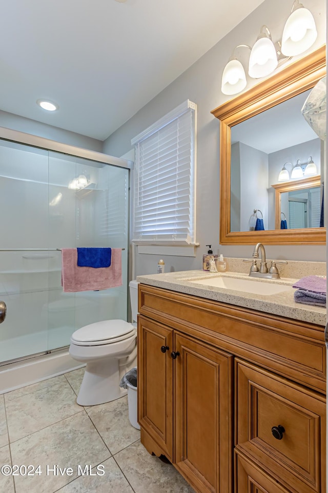 bathroom with tile patterned flooring, vanity, an enclosed shower, and toilet