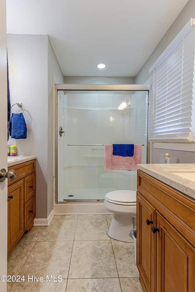 bathroom with tile patterned floors, vanity, toilet, and walk in shower