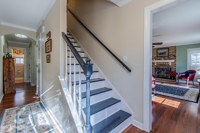 stairs featuring crown molding, a fireplace, and hardwood / wood-style flooring