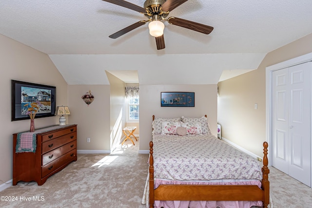 carpeted bedroom featuring a textured ceiling, a closet, vaulted ceiling, and ceiling fan