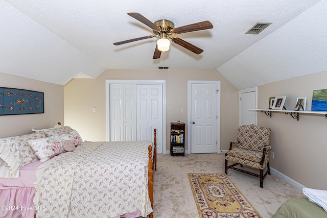 bedroom with light carpet, a textured ceiling, vaulted ceiling, and ceiling fan