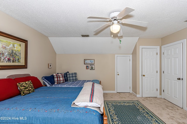 bedroom with a textured ceiling, light colored carpet, ceiling fan, and lofted ceiling