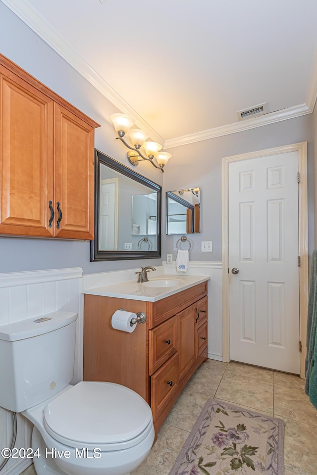 bathroom with tile patterned floors, vanity, toilet, and ornamental molding