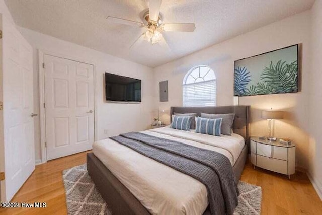 bedroom featuring ceiling fan, a textured ceiling, electric panel, and hardwood / wood-style flooring