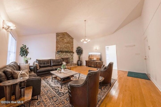 living room featuring a fireplace, an inviting chandelier, vaulted ceiling, and wood-type flooring