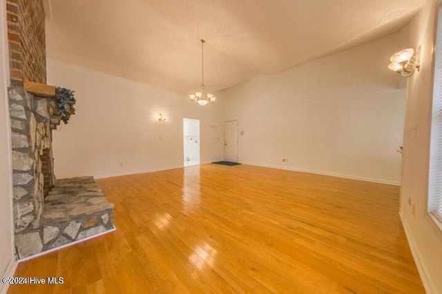 unfurnished living room featuring an inviting chandelier, hardwood / wood-style floors, and a fireplace