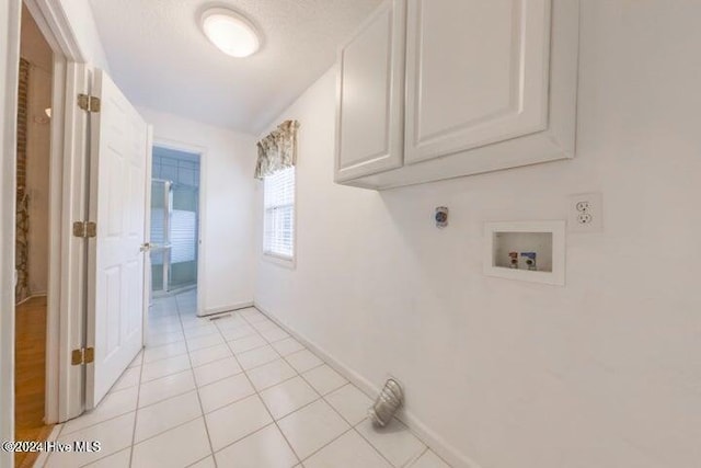 laundry room featuring cabinets, hookup for an electric dryer, light tile patterned floors, washer hookup, and a textured ceiling