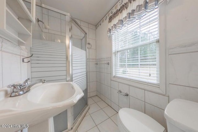 bathroom with sink, tile walls, a shower with shower door, toilet, and tile patterned floors