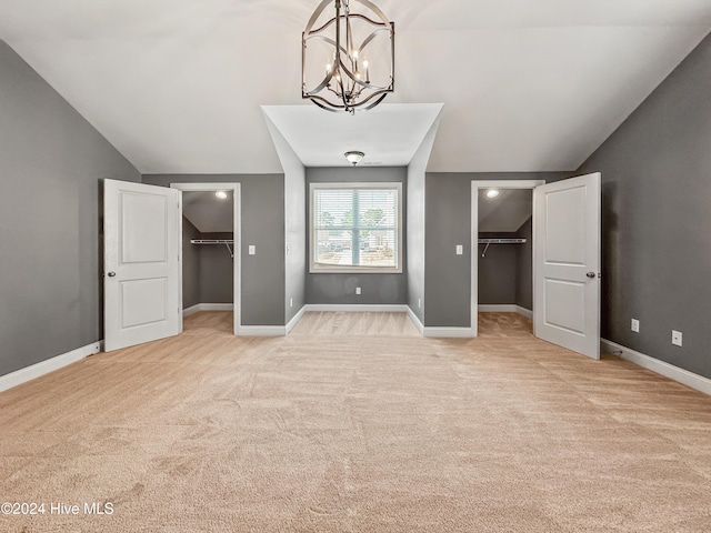 unfurnished bedroom featuring a walk in closet, vaulted ceiling, and a closet