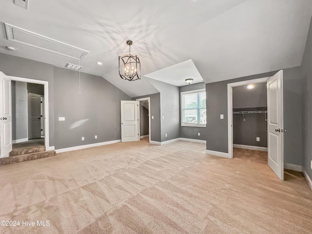 unfurnished bedroom featuring light carpet, a walk in closet, vaulted ceiling, and a closet