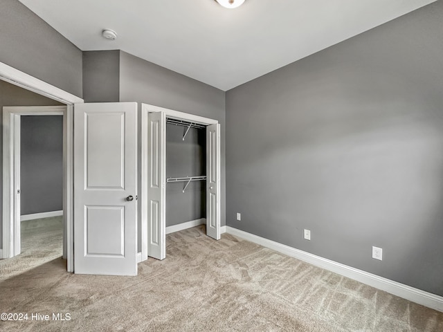 unfurnished bedroom with light carpet and a closet