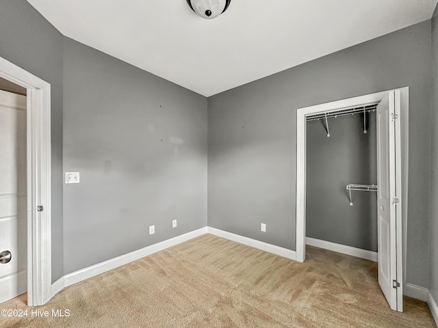 unfurnished bedroom featuring light colored carpet and a closet