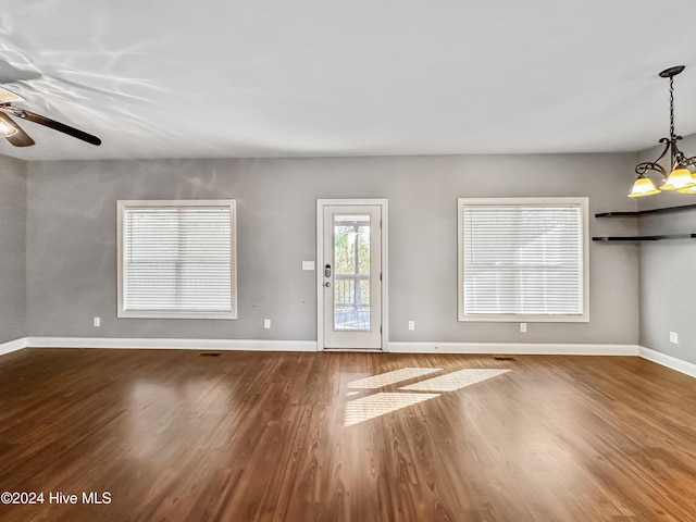 unfurnished living room with ceiling fan with notable chandelier and hardwood / wood-style flooring