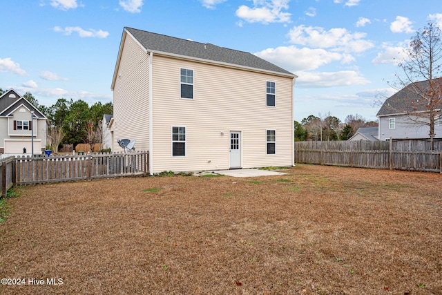 back of house with a lawn and a patio