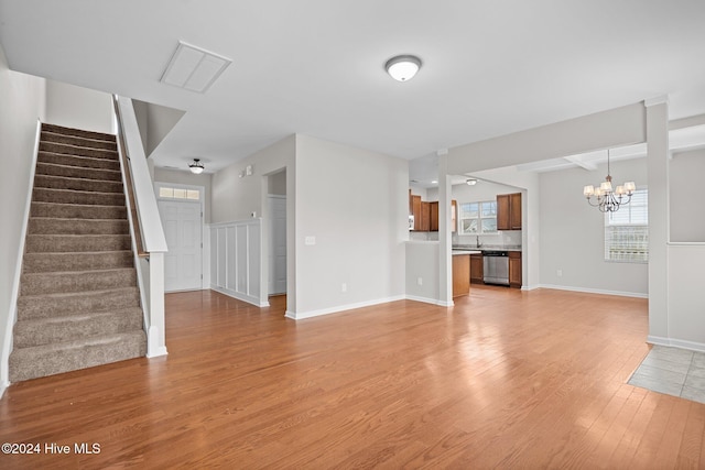 unfurnished living room featuring an inviting chandelier and light wood-type flooring